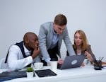 three-colleagues-engaged-in-teamwork-around-a